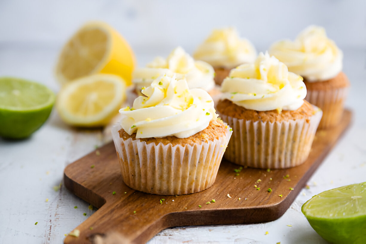 Delicious lemon-lime cupcakes with creamy frosting, displayed on a wooden board with lemon and lime halves in the background.