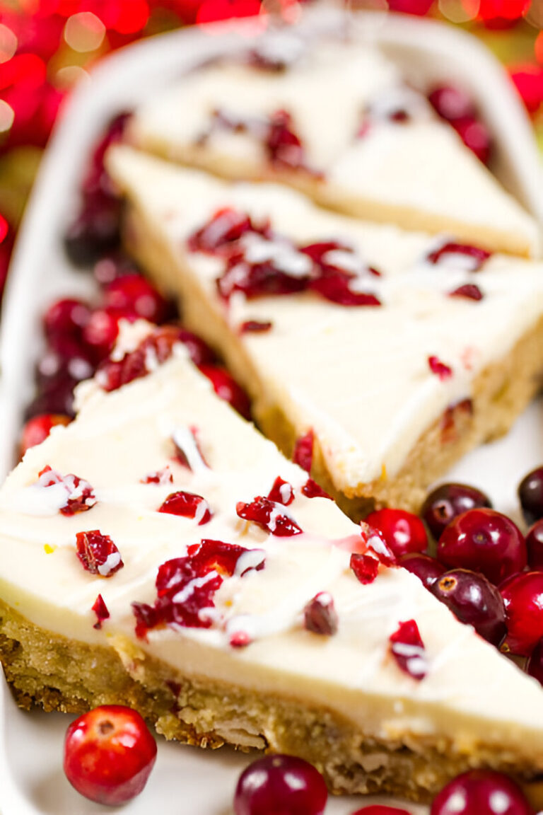 Slices of cranberry cheesecake on a white plate surrounded by fresh cranberries.