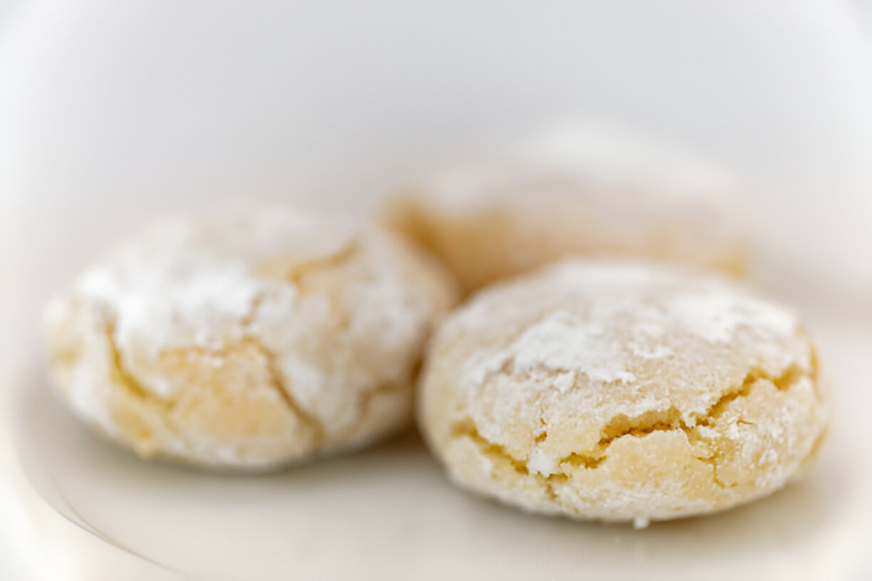 Three powdered sugar-coated cookies on a white plate.