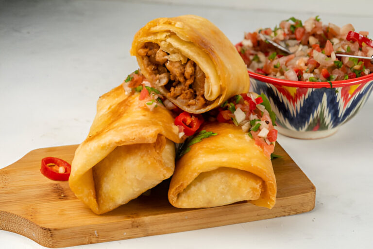 Three crispy rolled tacos filled with meat, served on a wooden board with a side of fresh salsa in a colorful bowl.