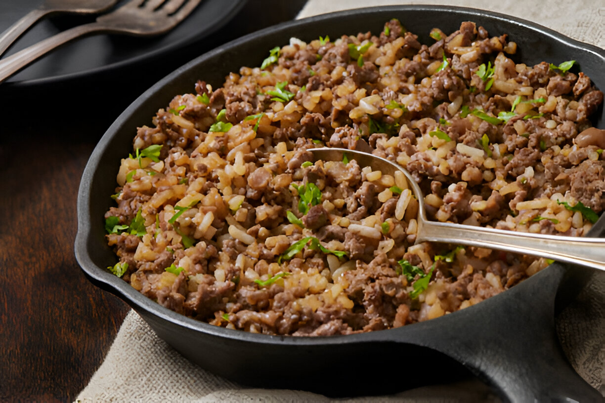 A skillet filled with a mixture of ground beef and rice, garnished with fresh parsley.