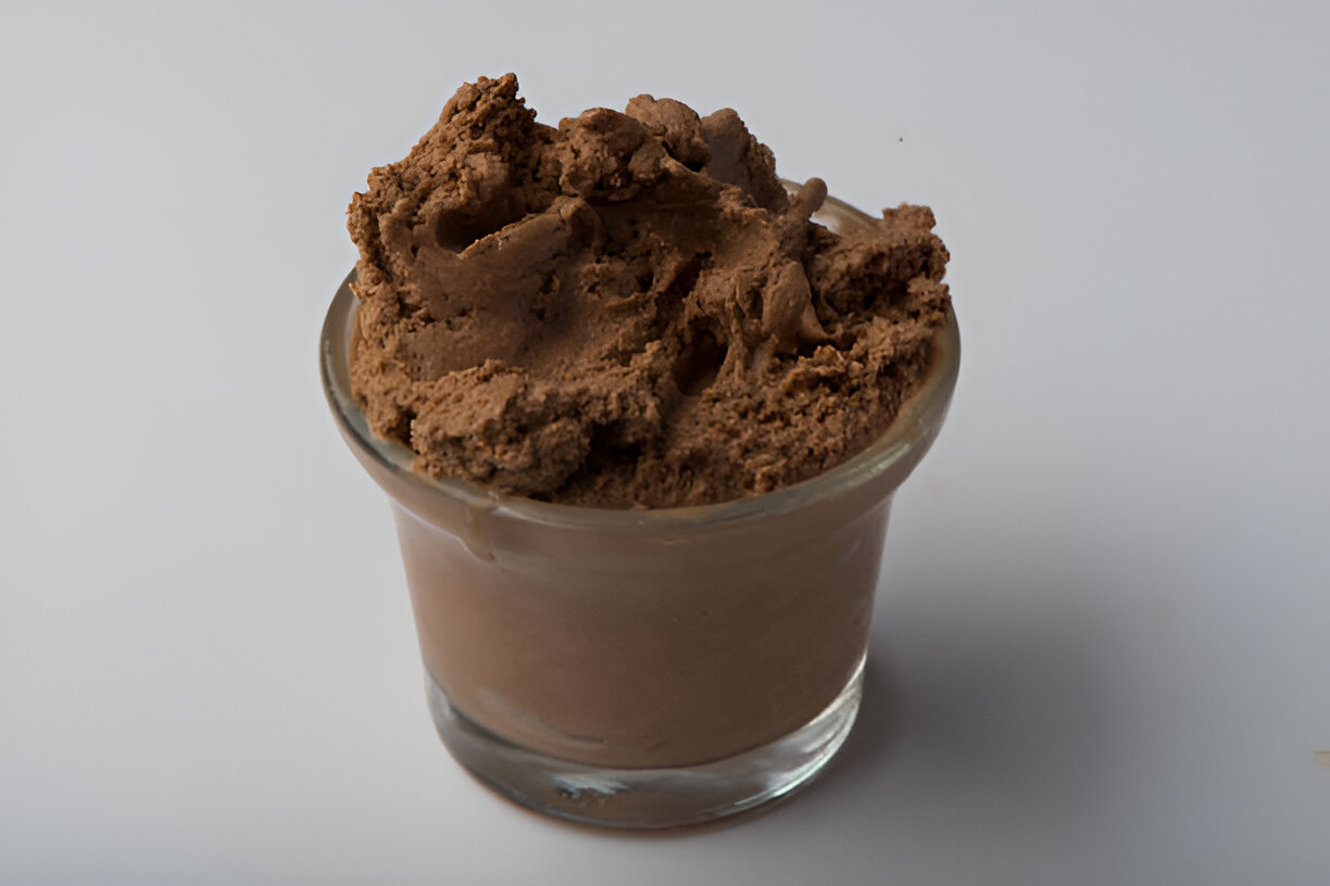 A small glass cup filled with creamy chocolate mousse.
