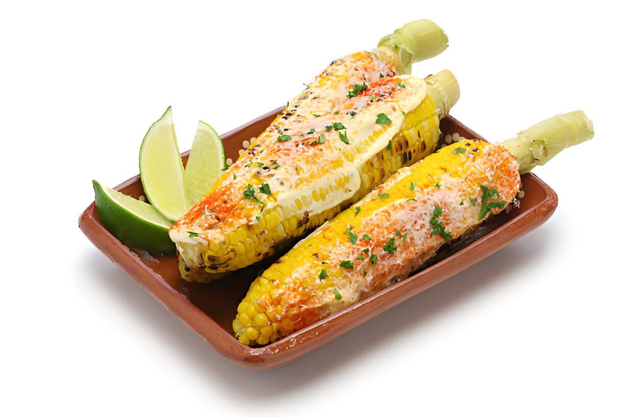 Two elote corn cobs topped with cheese, spices, and garnished with lime wedges on a brown plate.