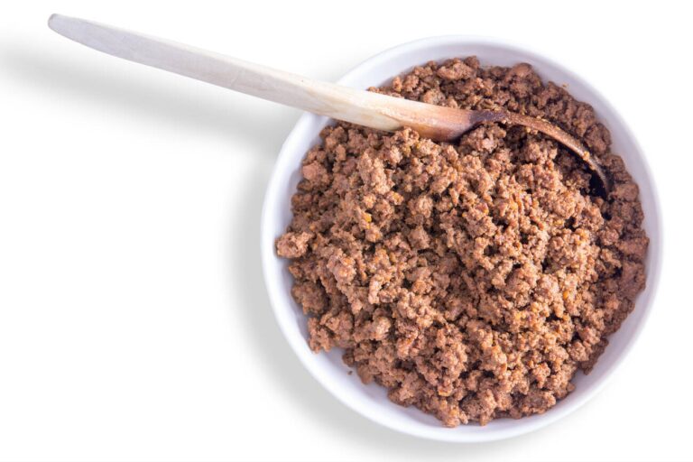 A bowl of textured brown food with a wooden spoon on the side.