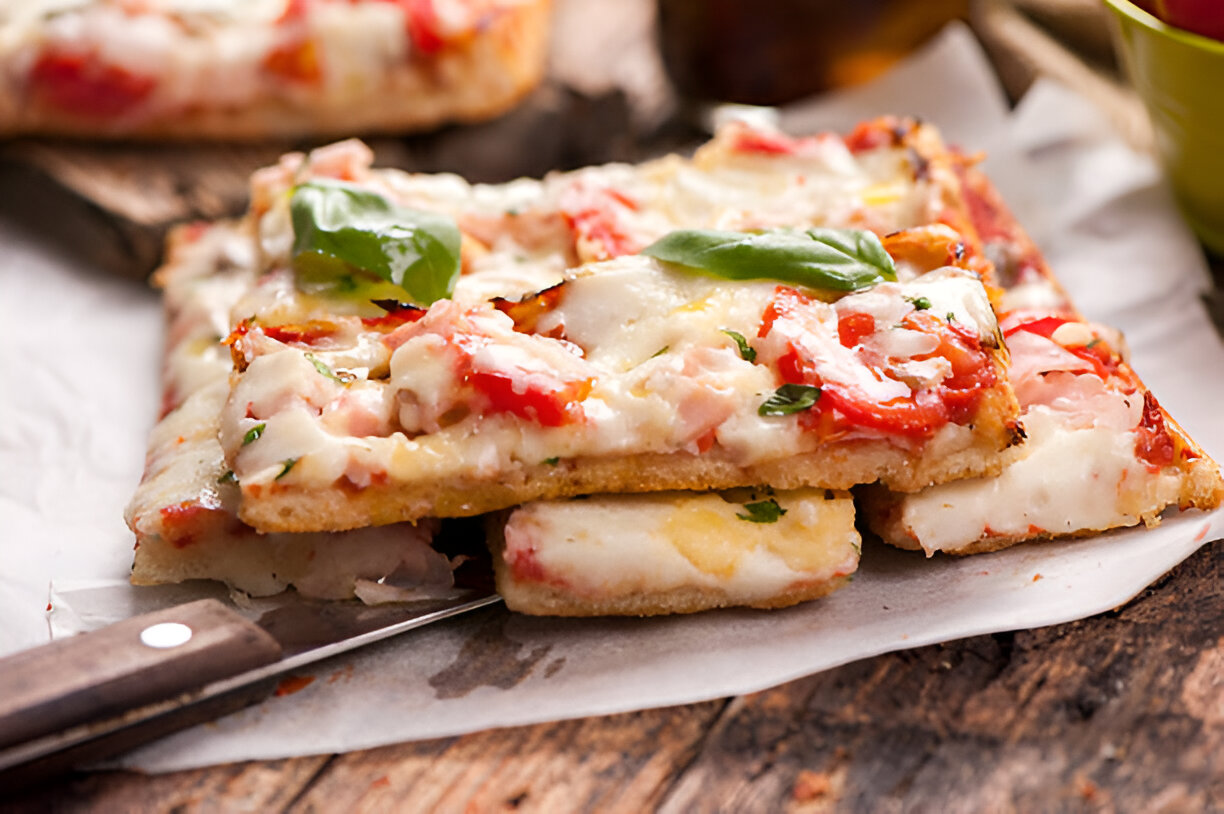 Delicious slices of pizza topped with cheese, tomatoes, and fresh basil, resting on a wooden surface.