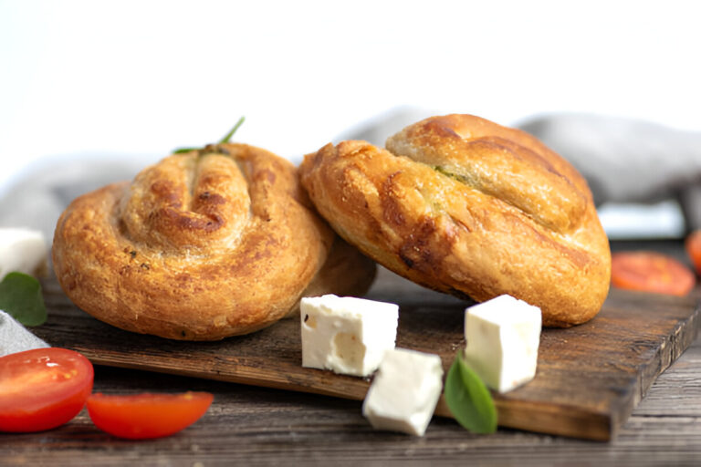 Two freshly baked rolls with cheese and sliced tomatoes on a wooden board.