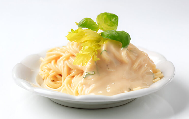A plate of creamy pasta with green garnish on top.