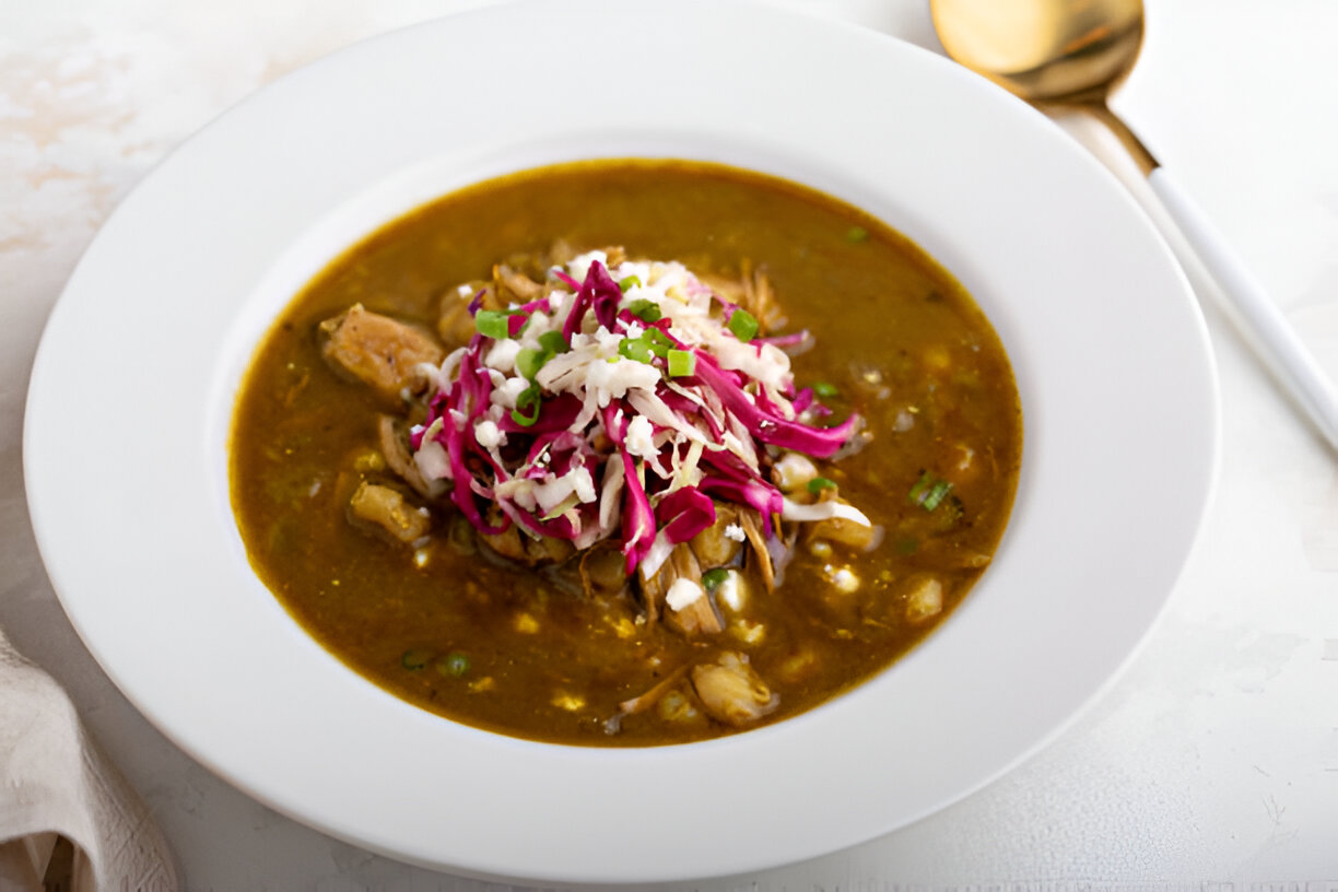 A bowl of hearty stew with a topping of shredded cabbage and green onions