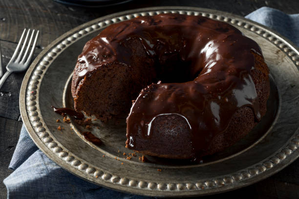 A delicious chocolate bundt cake on a silver platter with a fork beside it.