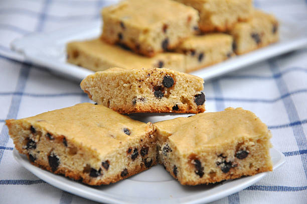 Delicious chocolate chip blondies served on a plate, with more in the background.