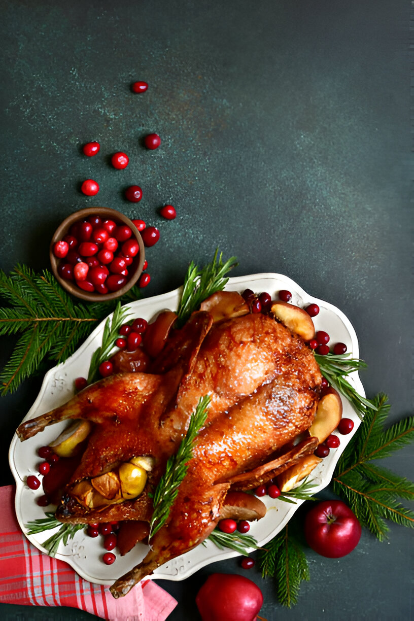 Roasted duck garnished with cranberries and greenery on a decorative platter