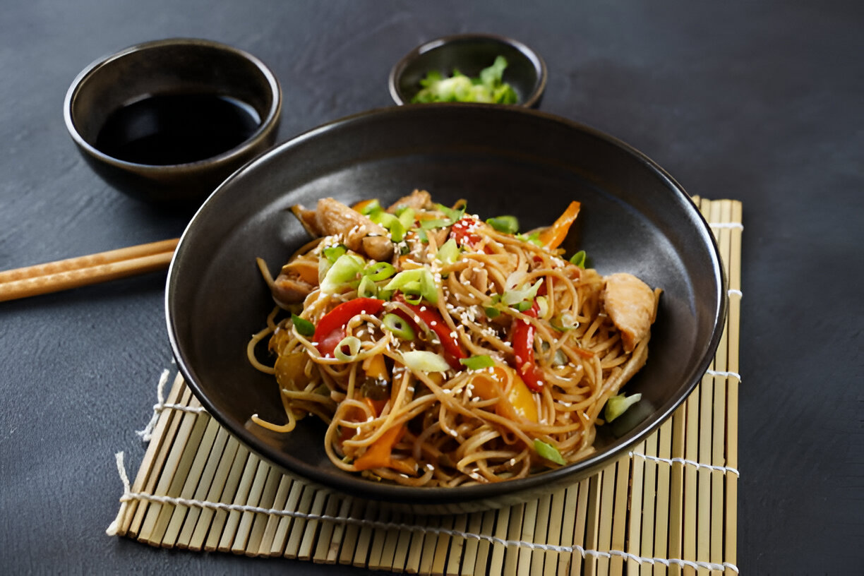 A delicious serving of chicken stir-fried noodles topped with green onions and sesame seeds.
