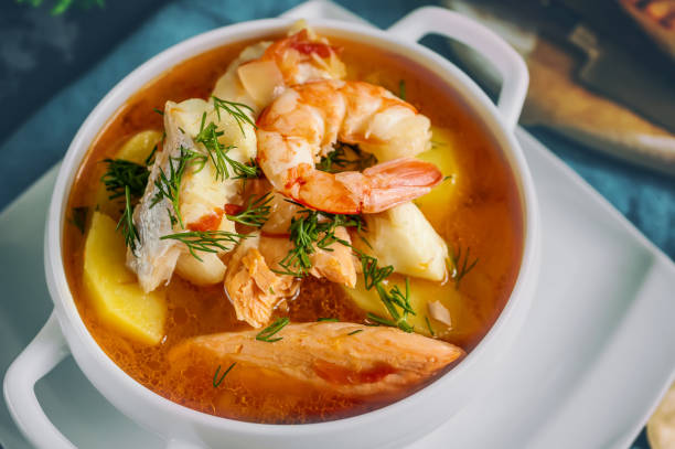 A bowl of seafood soup with shrimp, fish, and vegetables.