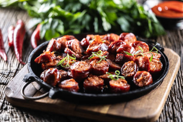 A delicious plate of cooked sausage slices garnished with green onions on a black serving platter.