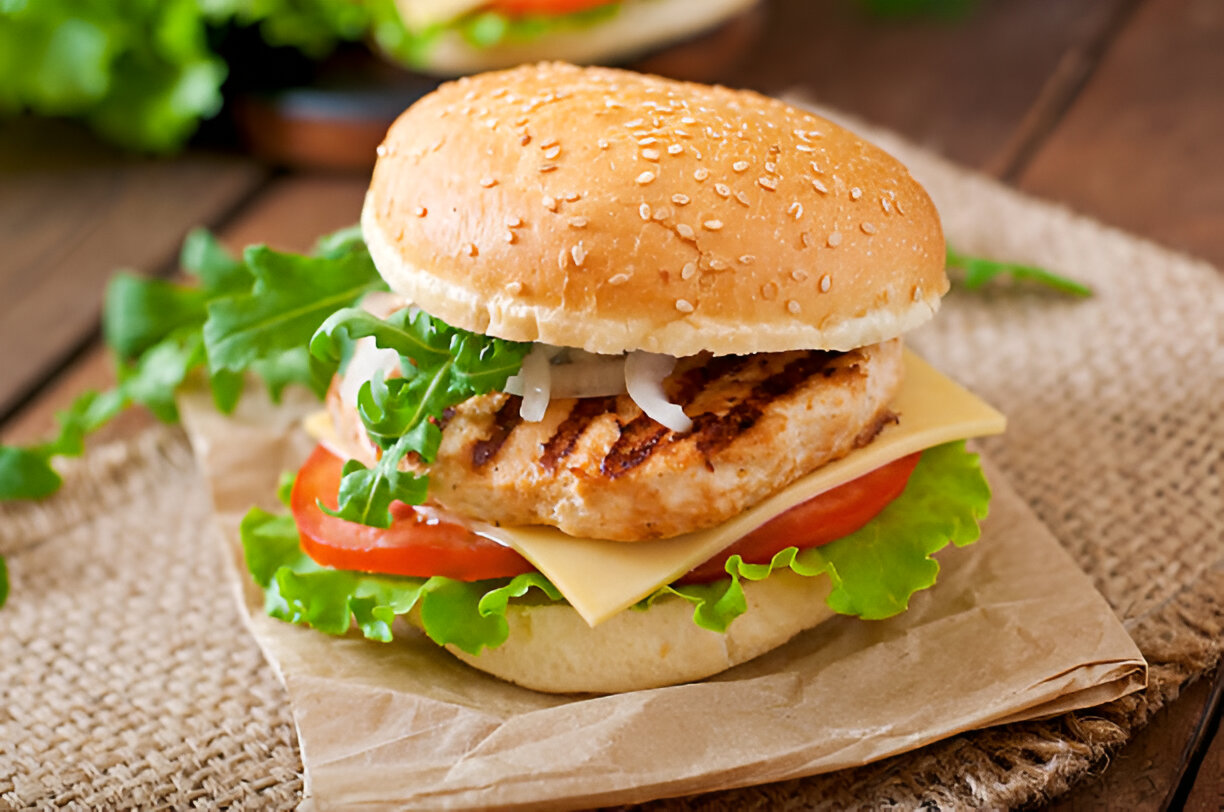 A delicious grilled chicken burger with lettuce, tomato, and cheese in a sesame seed bun
