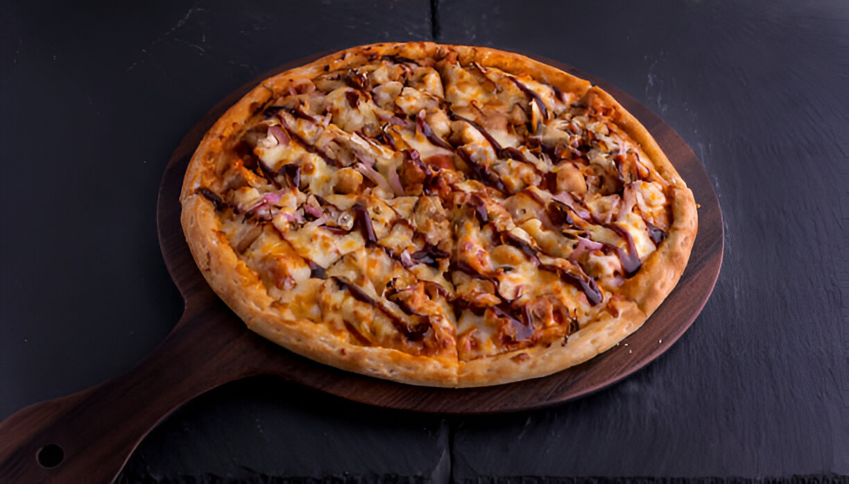 A delicious barbecue chicken pizza on a wooden serving board.