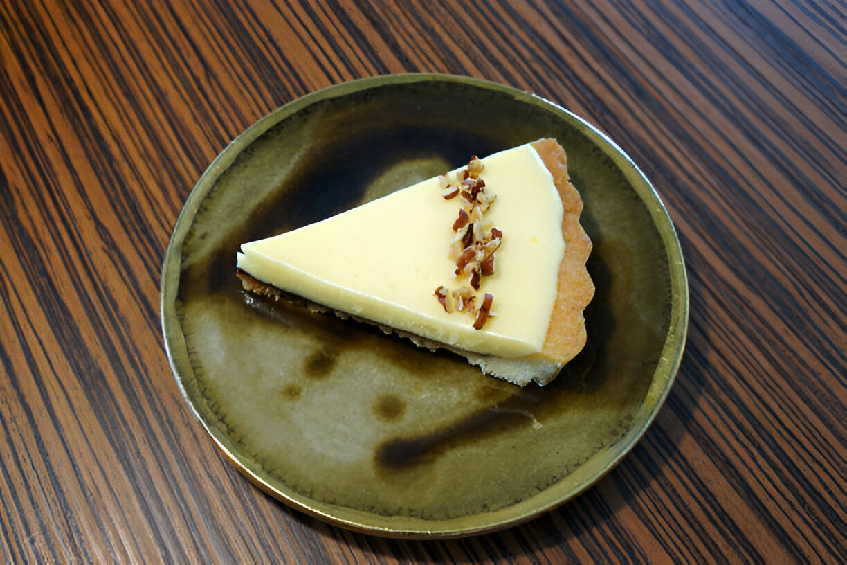 A slice of creamy pie on a green plate, garnished with chopped nuts.