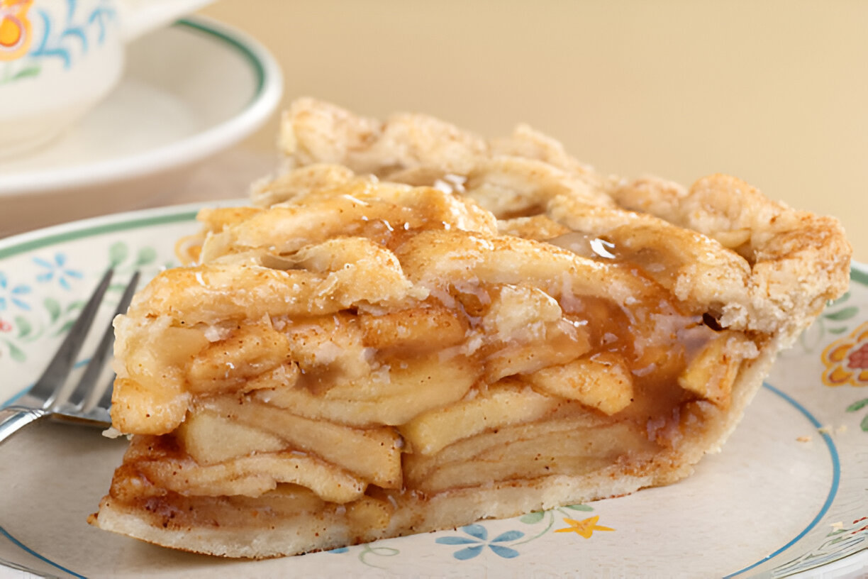 A slice of apple pie on a floral plate, with a fork beside it.