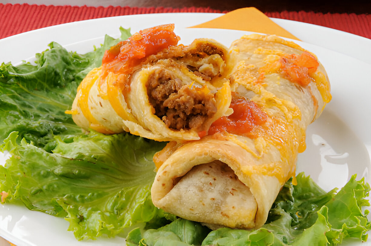 Two delicious burritos filled with ground meat and topped with melted cheese and salsa on a bed of fresh lettuce.