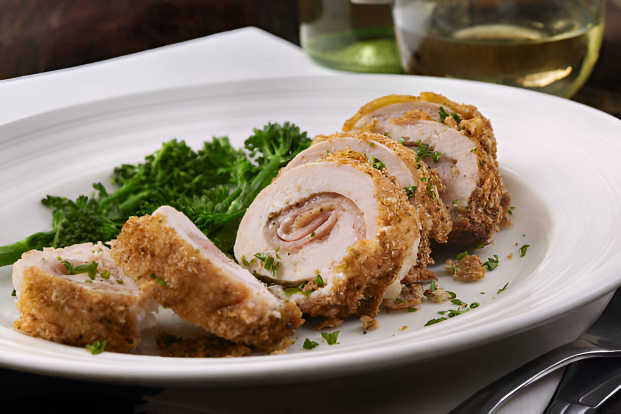 Sliced chicken roulade served on a white plate with green herbs.