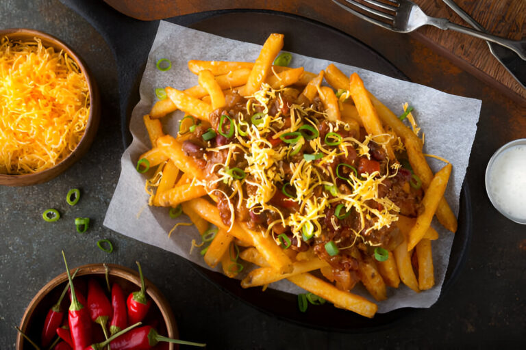 Plate of loaded fries topped with chili, cheese, and green onions.