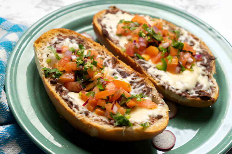 Two delicious halves of bread topped with melted cheese, black beans, and fresh salsa on a green plate.