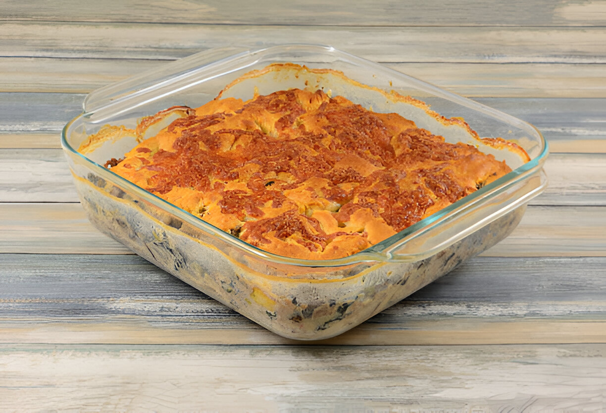 Baked casserole dish with a golden crust on top, sitting on a wooden table.