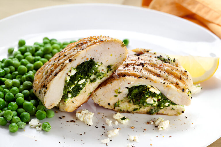 Grilled chicken breast stuffed with spinach and feta cheese served with green peas and a lemon slice.