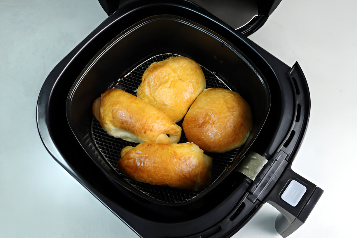 Air fryer containing golden-brown stuffed rolls.