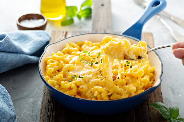 A creamy bowl of macaroni and cheese topped with fresh herbs, served in a blue dish.
