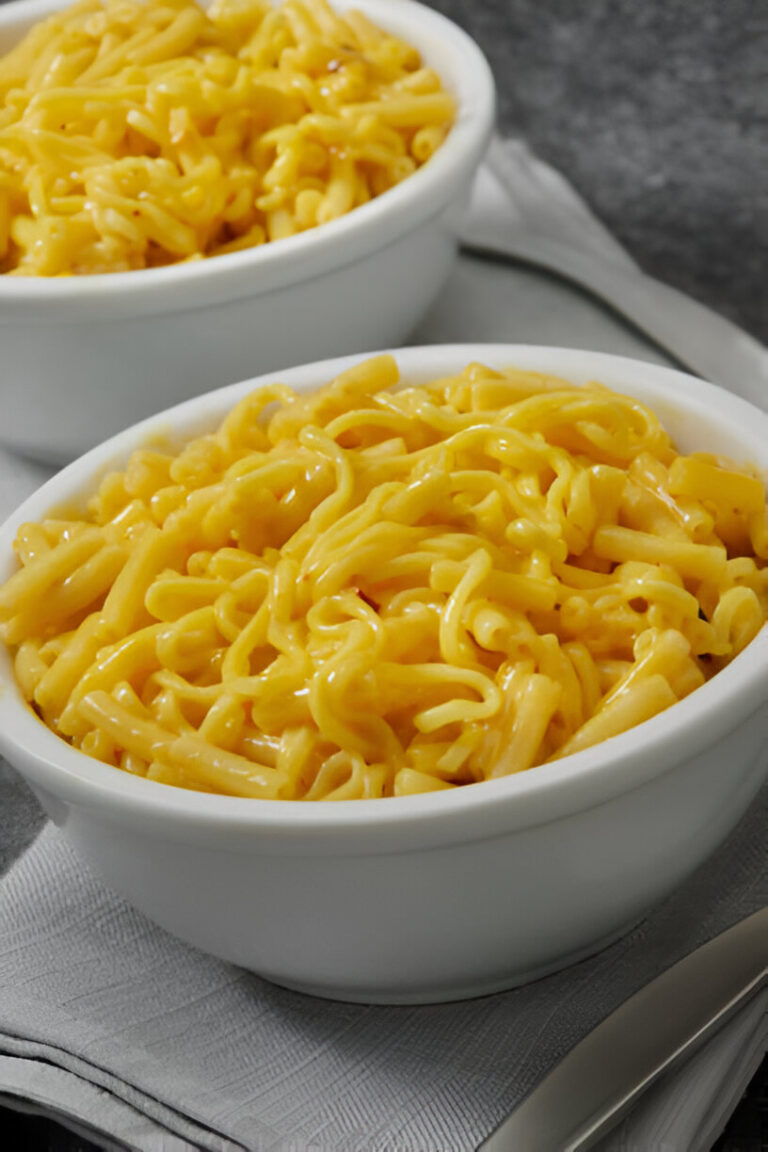 Bowls of creamy macaroni and cheese served on a textured gray surface