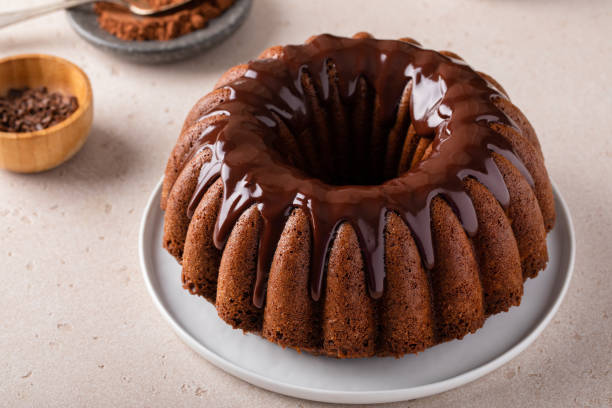 A delicious chocolate bundt cake drizzled with chocolate glaze, presented on a white plate.