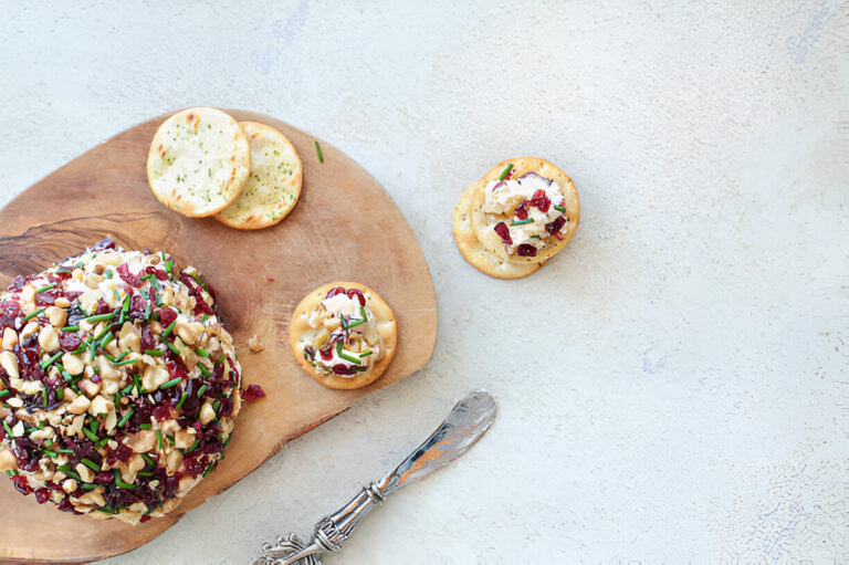A festive cheese ball topped with nuts and herbs, served with crackers.