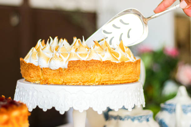 A beautifully decorated cake on a white stand, being served with a cake slicer.