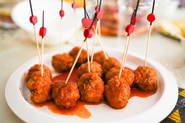 A plate of meatballs with toothpicks topped with red decorations