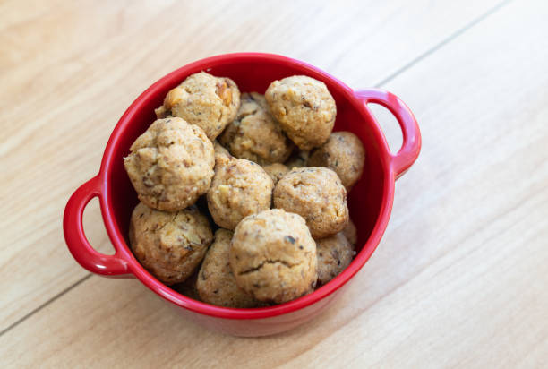 A bowl of homemade cookies in a red dish on a wooden surface.