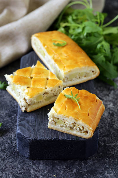 Sliced savory pastry filled with meat and herbs displayed on a wooden board