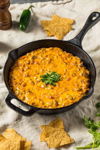 A creamy cheese dip in a cast iron skillet, garnished with fresh cilantro, served with tortilla chips.