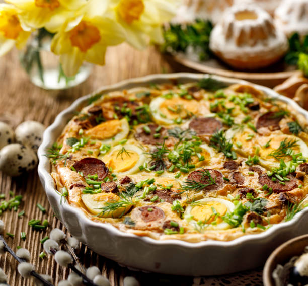A delicious frittata garnished with slices of boiled egg, herbs, and sausage, surrounded by decorative elements for a festive atmosphere.